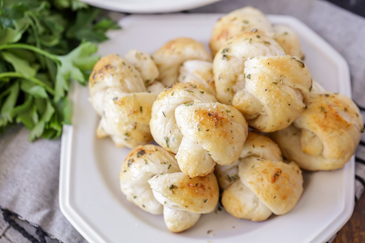 Italian Side Dishes - Easy garlic knots piled on a white plate for serving.