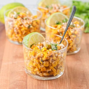Esquites recipe served in cups with cilantro, Cotija and more on top.