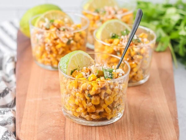 Esquites recipe served in cups with cilantro, Cotija and more on top.
