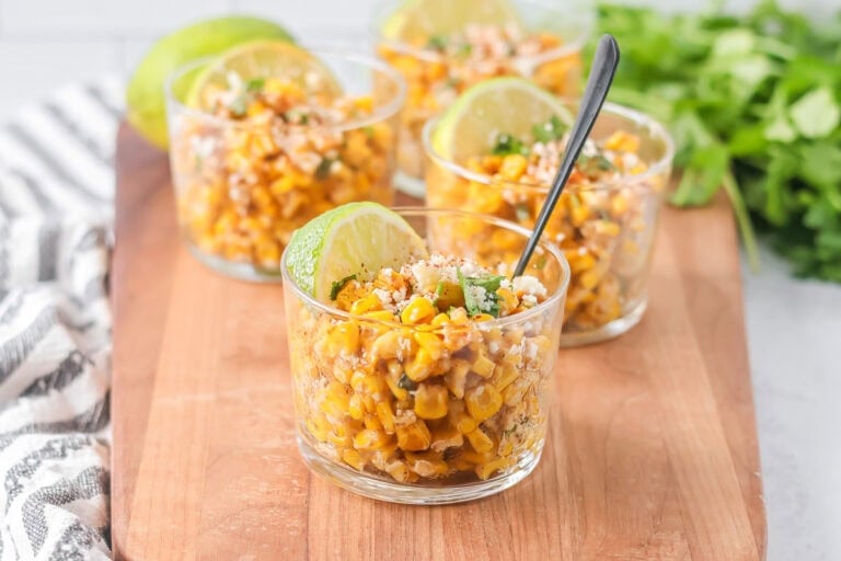 Esquites recipe served in cups with cilantro, Cotija and more on top.