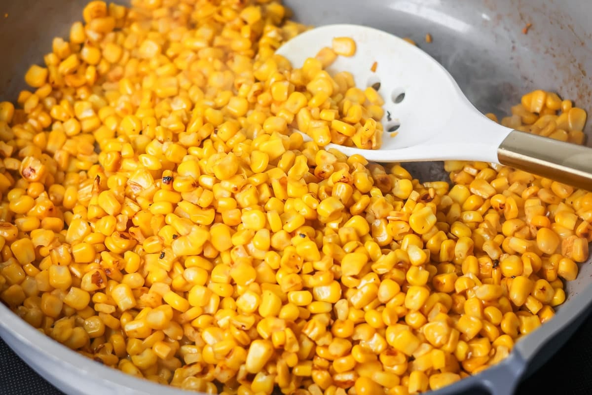 Corn being cooked in a skillet.