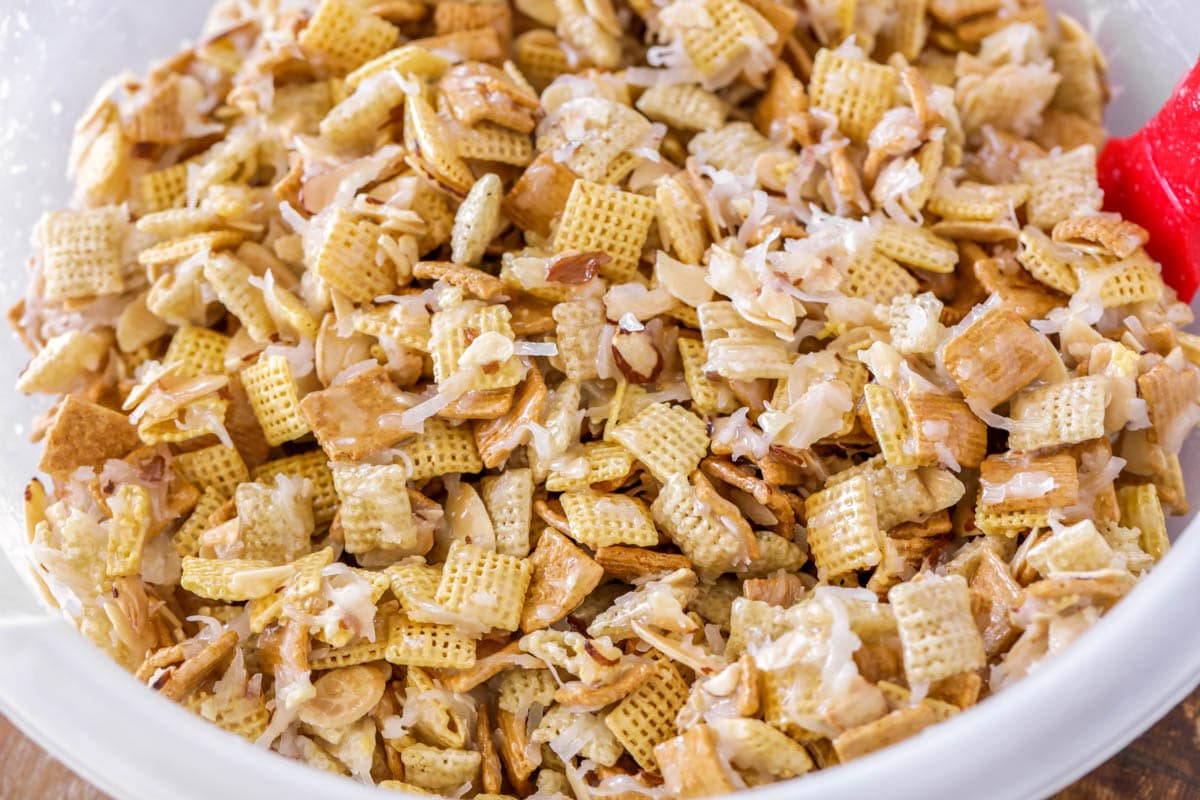 Homemade sweet chex mixed in a plastic bowl and covered in coconut