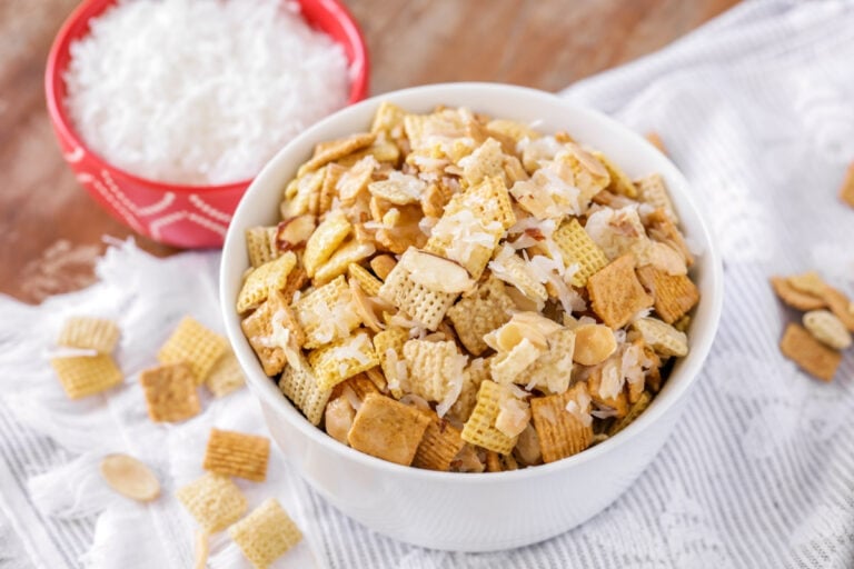 Sweet chex mix recipe in white bowl with ingredients around it.