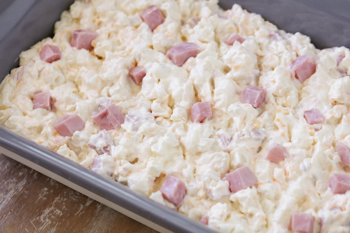 Creamy potatoes topped with ham cubes in a baking dish