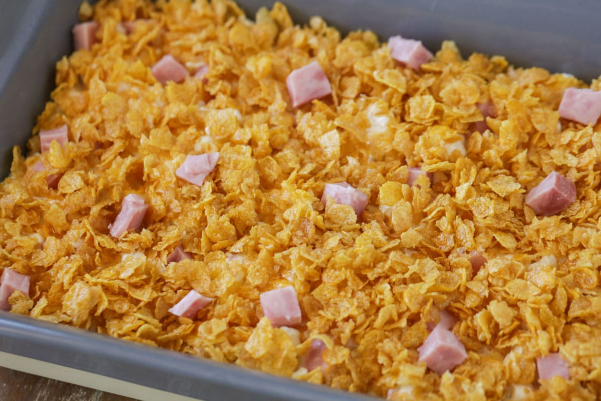 ham and potato casserole topped with corn flakes in a baking dish