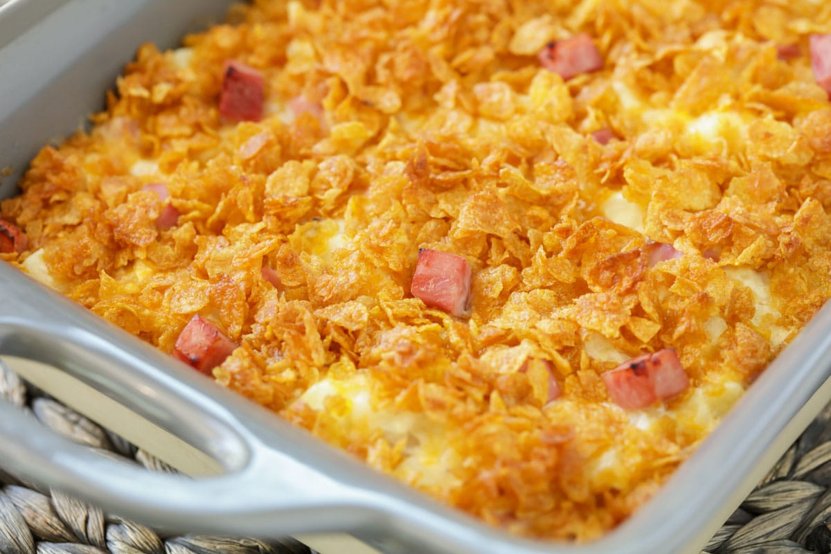 Ham and potato casserole topped with corn flakes in a baking dish.