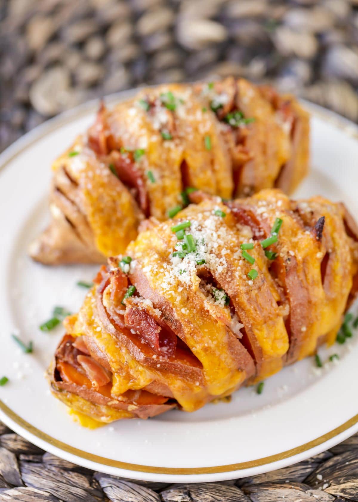 Chive sprinkled cheesy hasselback sweet potatoes served on a white plate