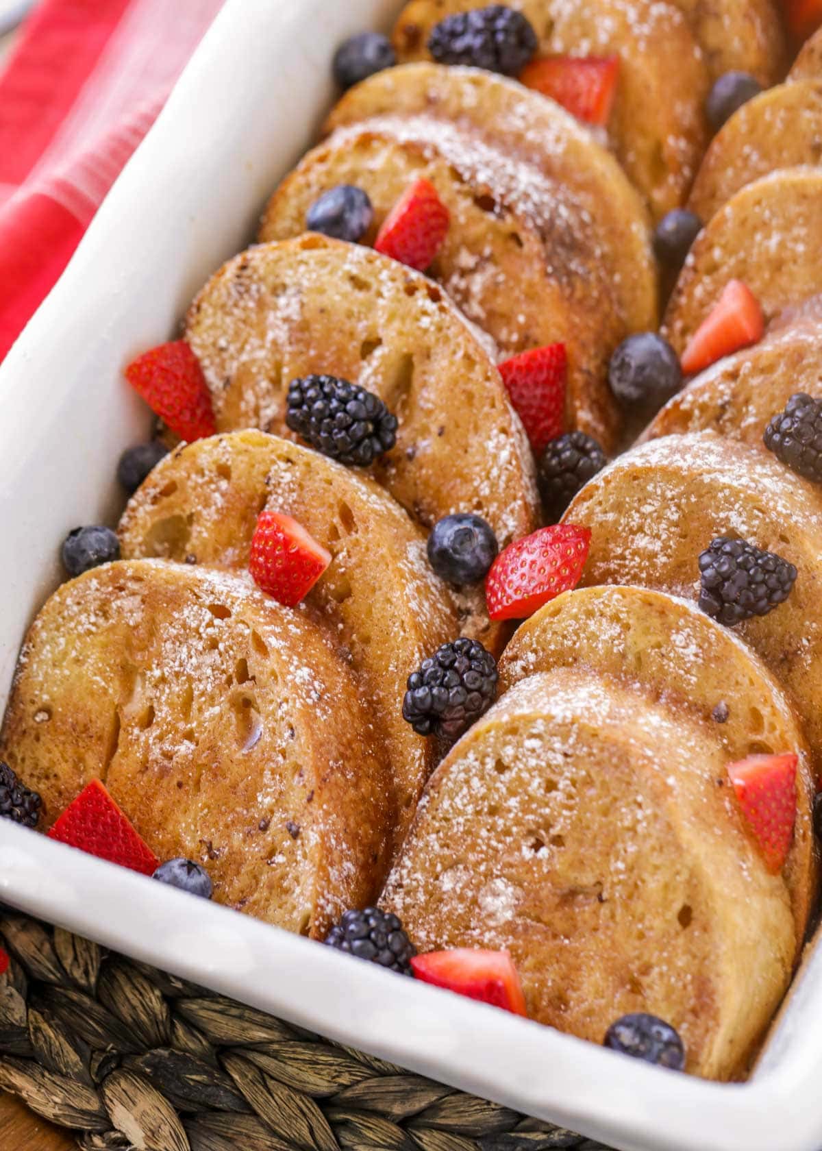 Oven french toast in a white baking dish topped with fresh berries
