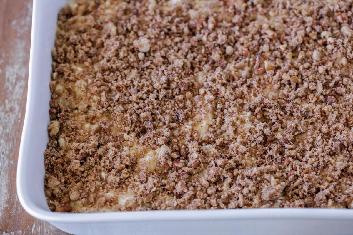 Streusel on top of cake layer in a white baking dish.