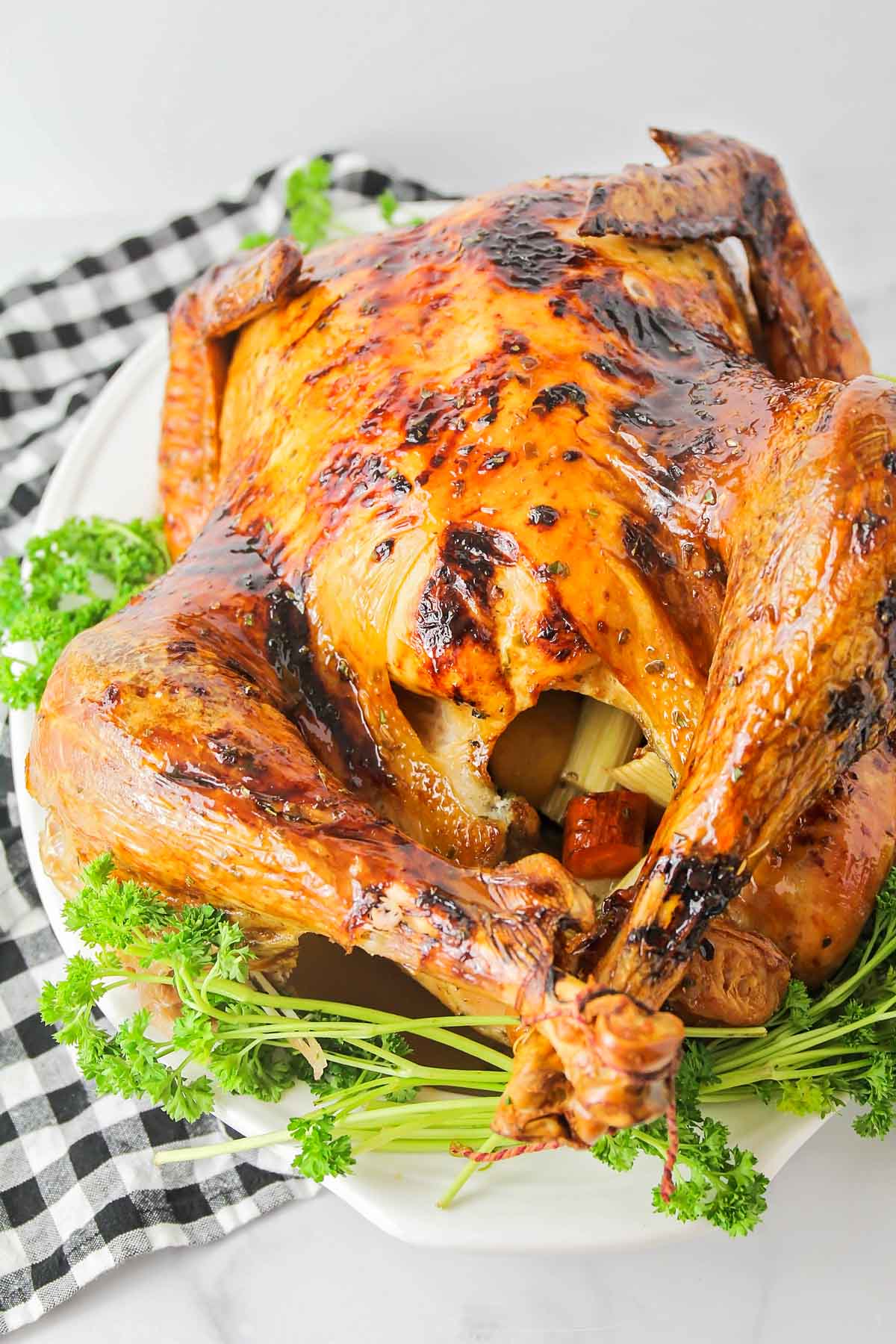 Close up of perfectly glazed roast turkey on a white platter with parsley