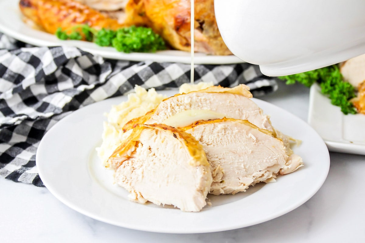 Sliced turkey with gravy pouring from a gravy boat
