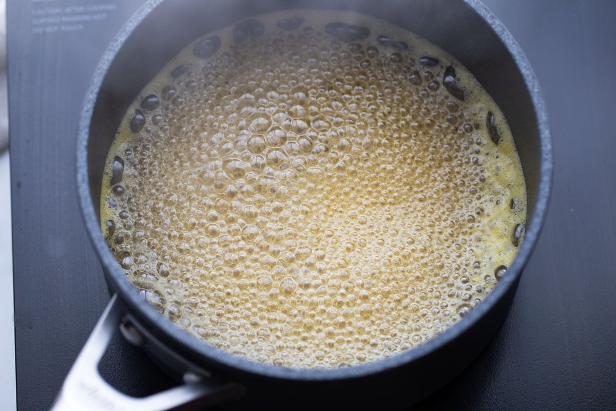 Fruit salad dressing cooking in a pot on the stove.