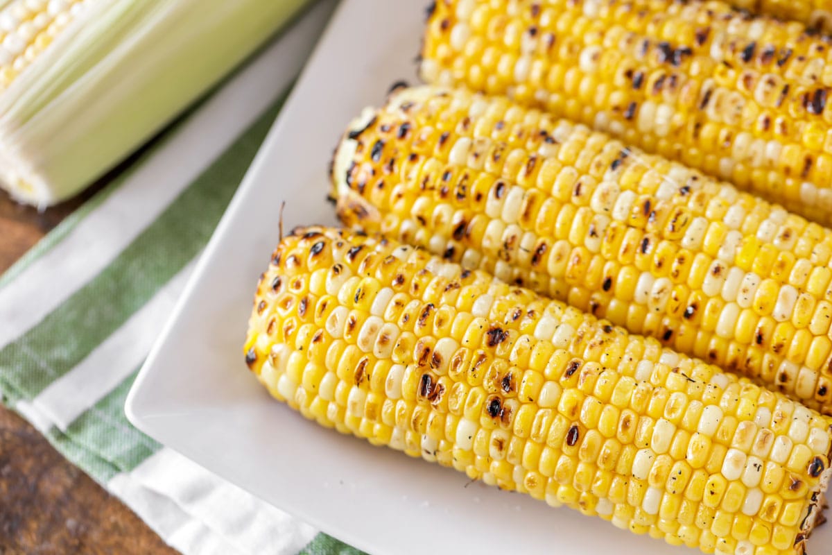 Grilled corn on the cob served on a white platter.