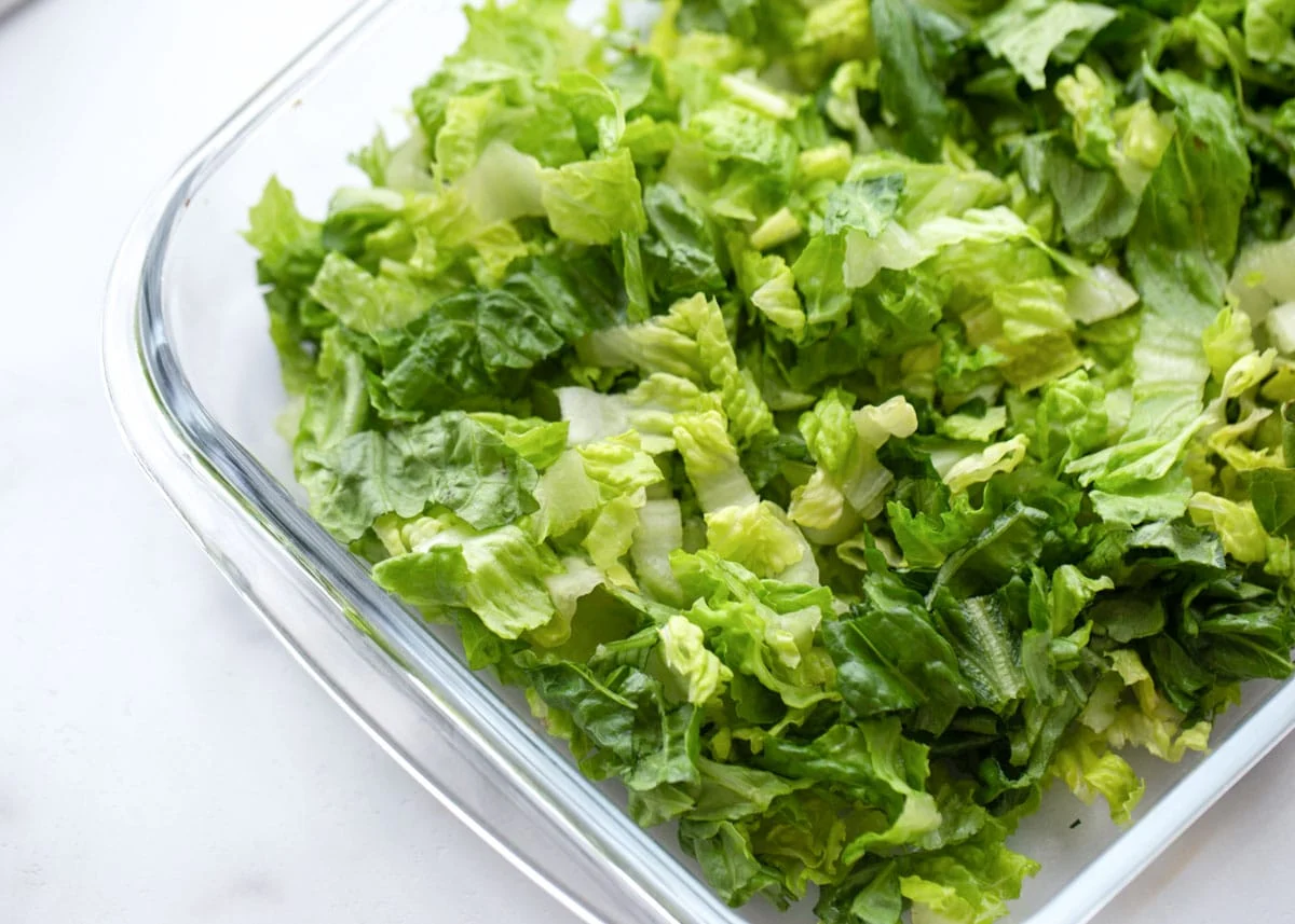 Lettuce layer of tortellini salad in a baking dish.