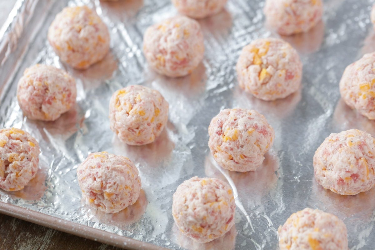 uncooked sausage balls with cream cheese on a baking sheet