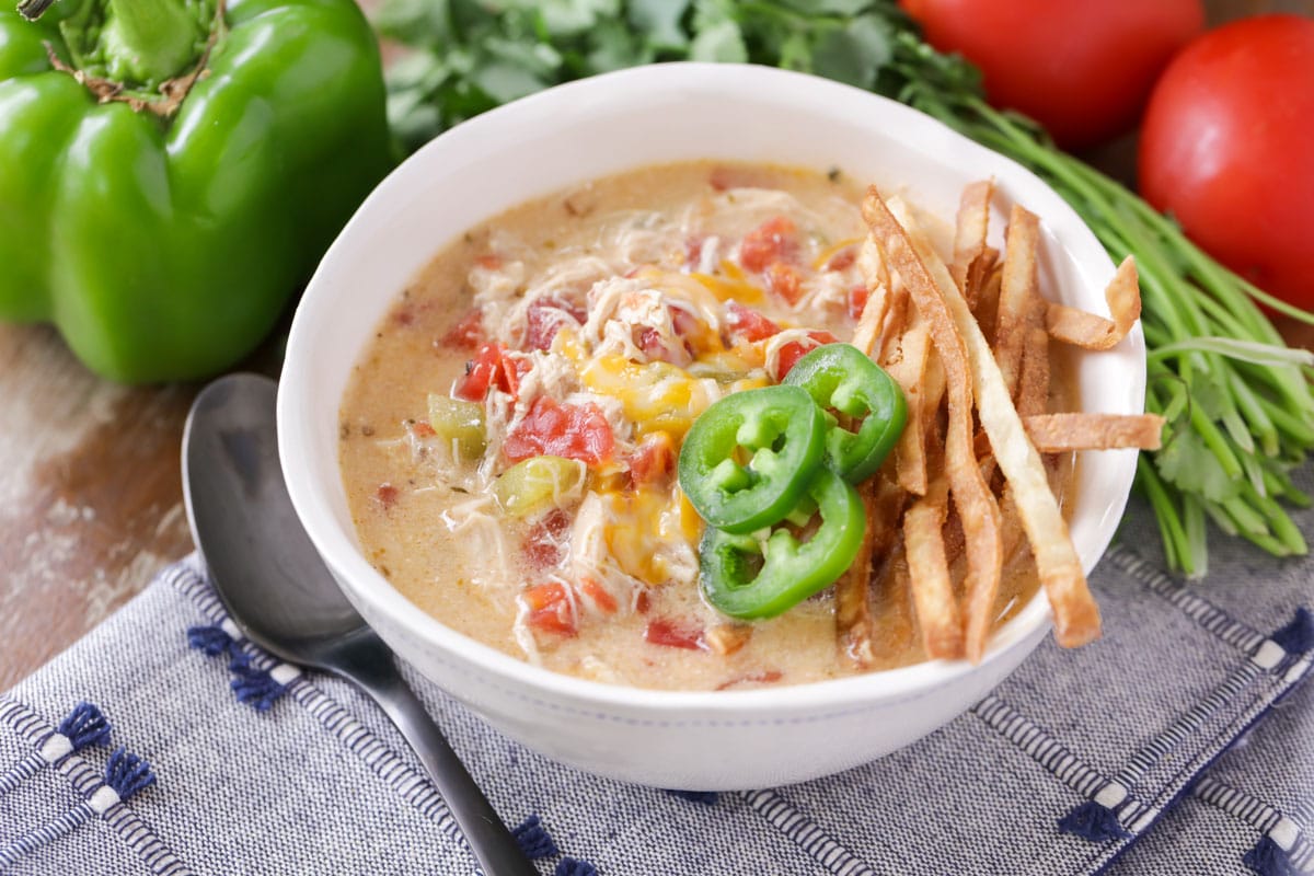 King Ranch Chicken Soup topped with crispy tortilla strips and jalapeno pepper slices in a white bowl. 