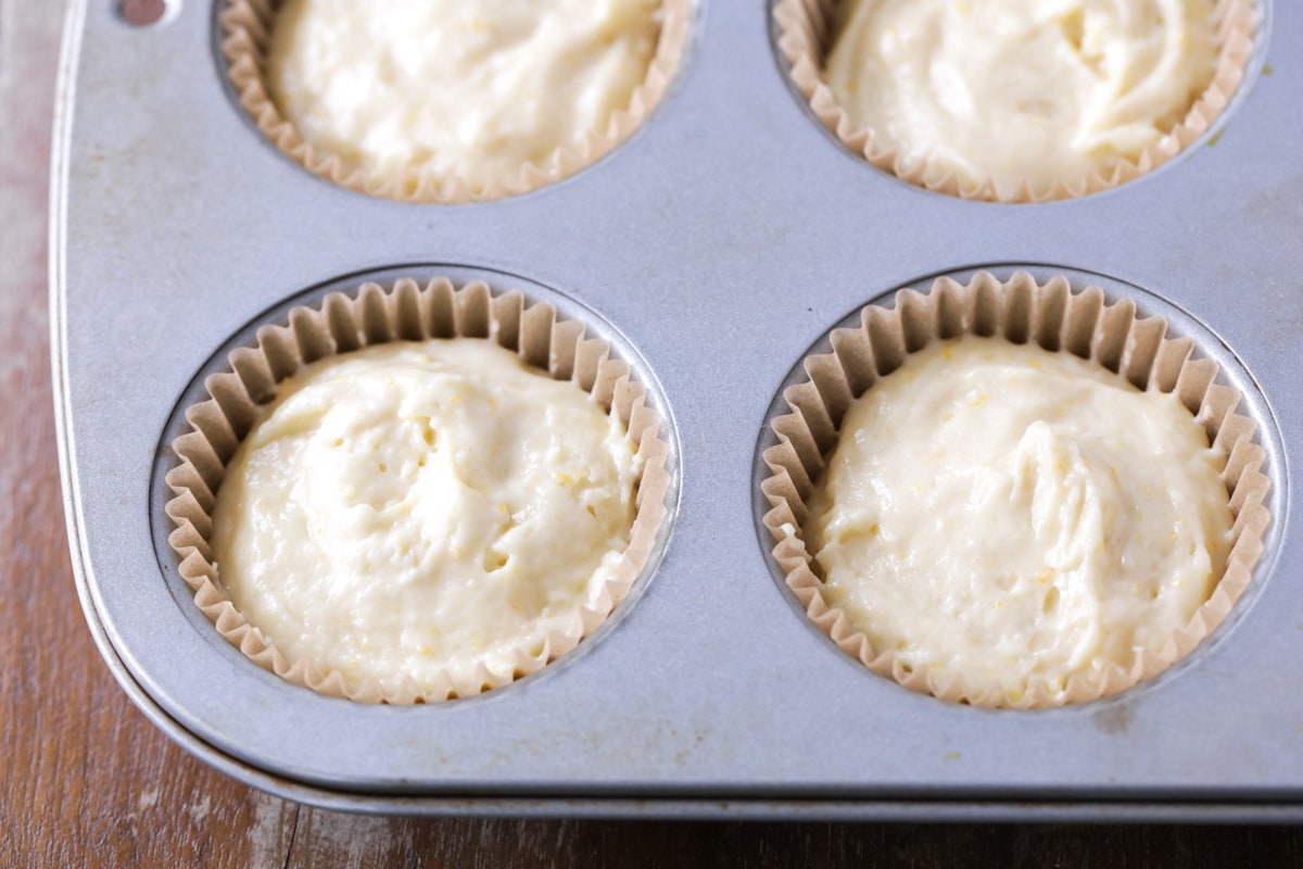 unbaked orange muffins in a muffin tin