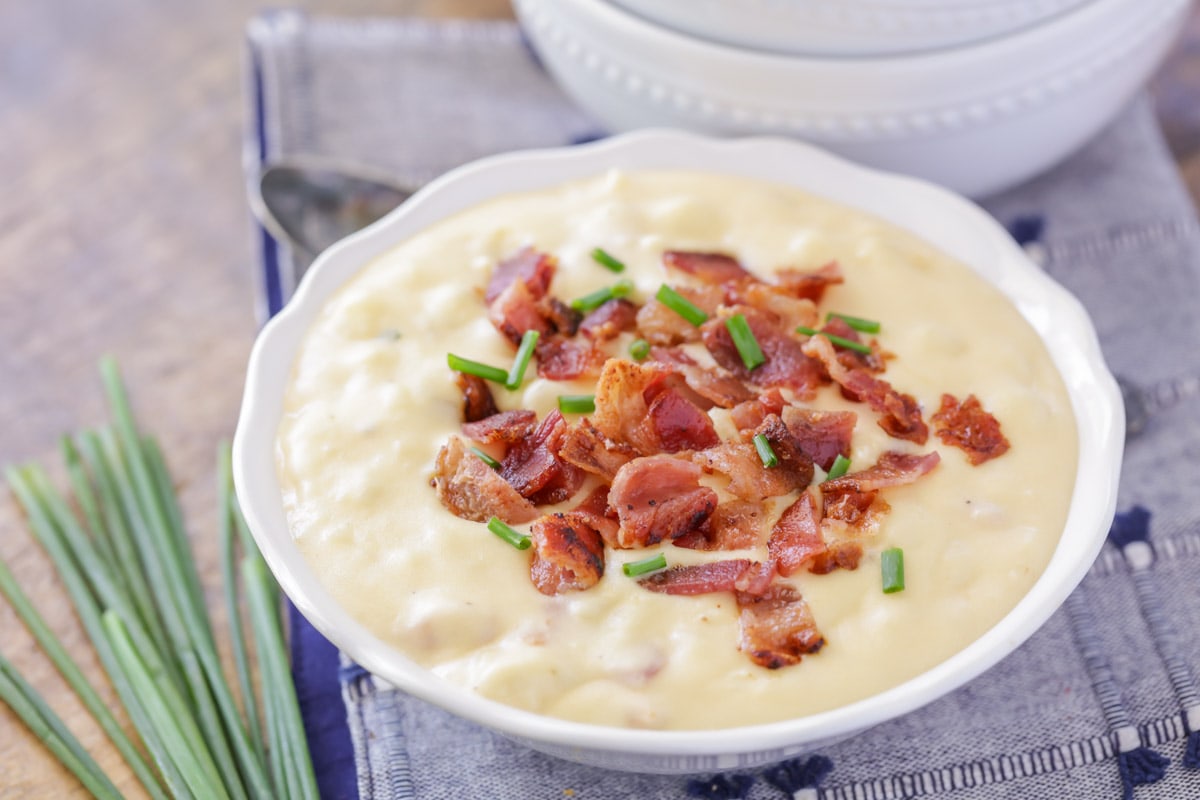 White bowl filled with potato and bacon soup topped with crumbled bacon.