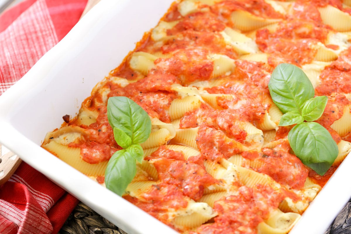 Baked stuffed shells layered in a white baking dish.