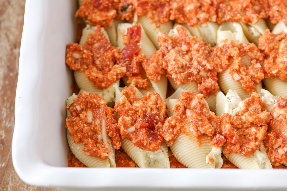 Cheese stuffed shells covered with sauce in a baking dish