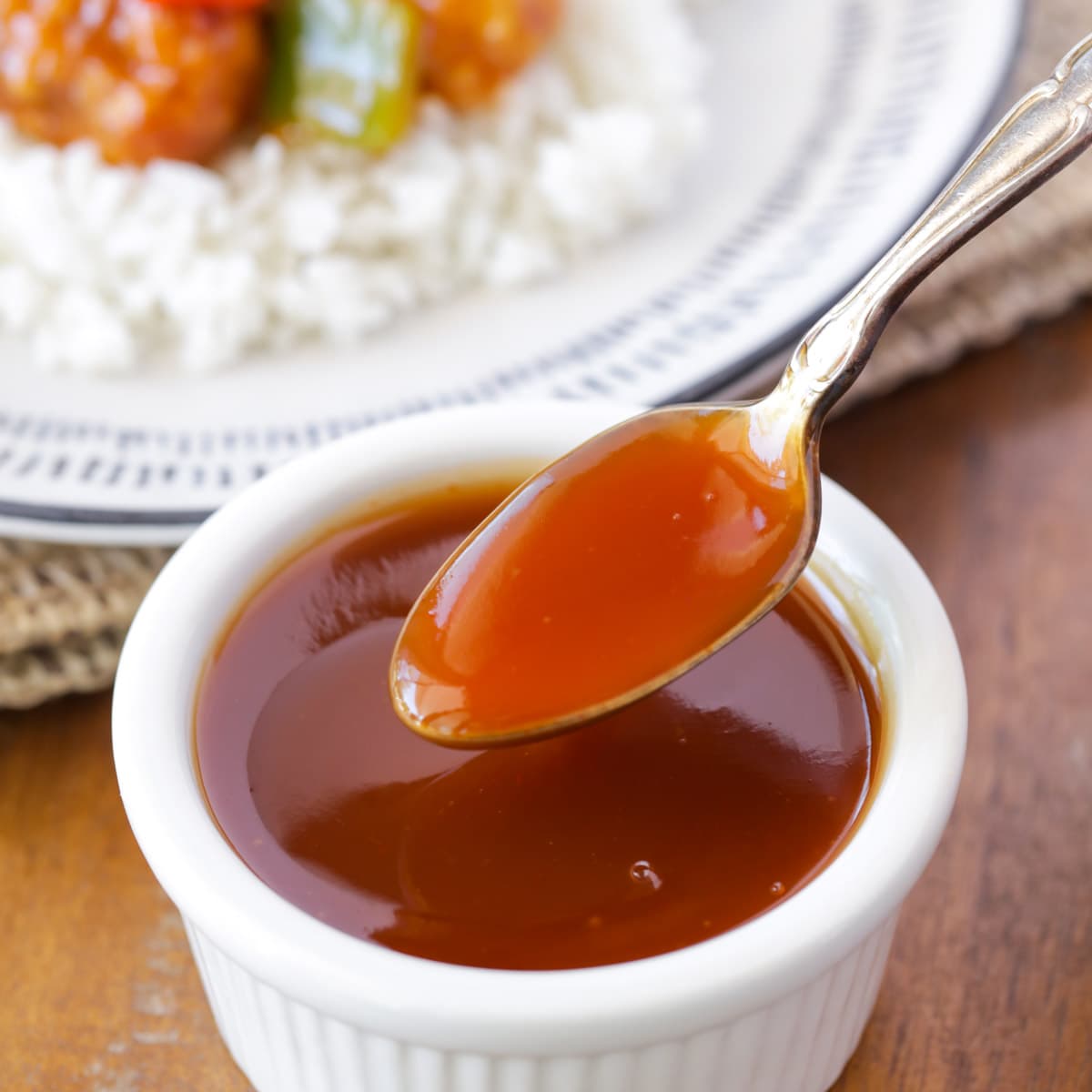 Bowl of sweet and sour sauce with a metal spoon