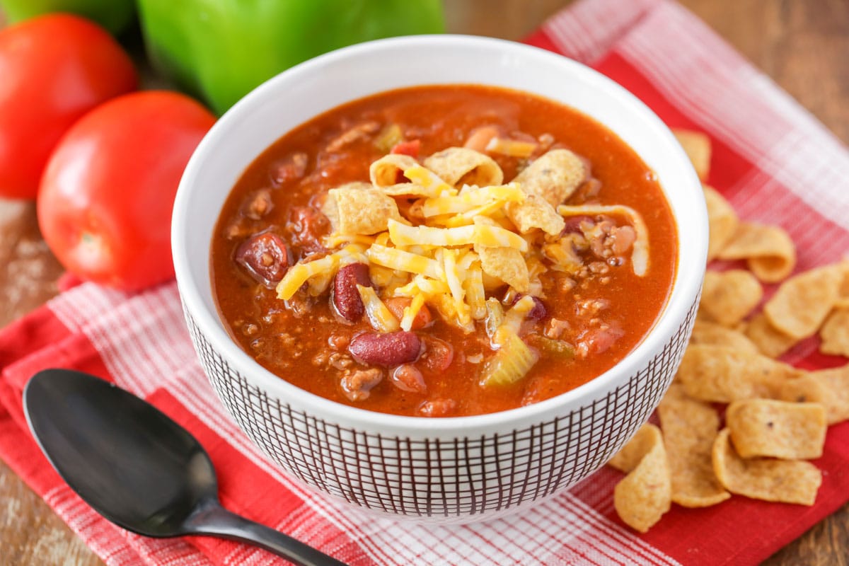 A white bowl of Wendy's Chili recipe topped with shredded cheese and Frito chips.