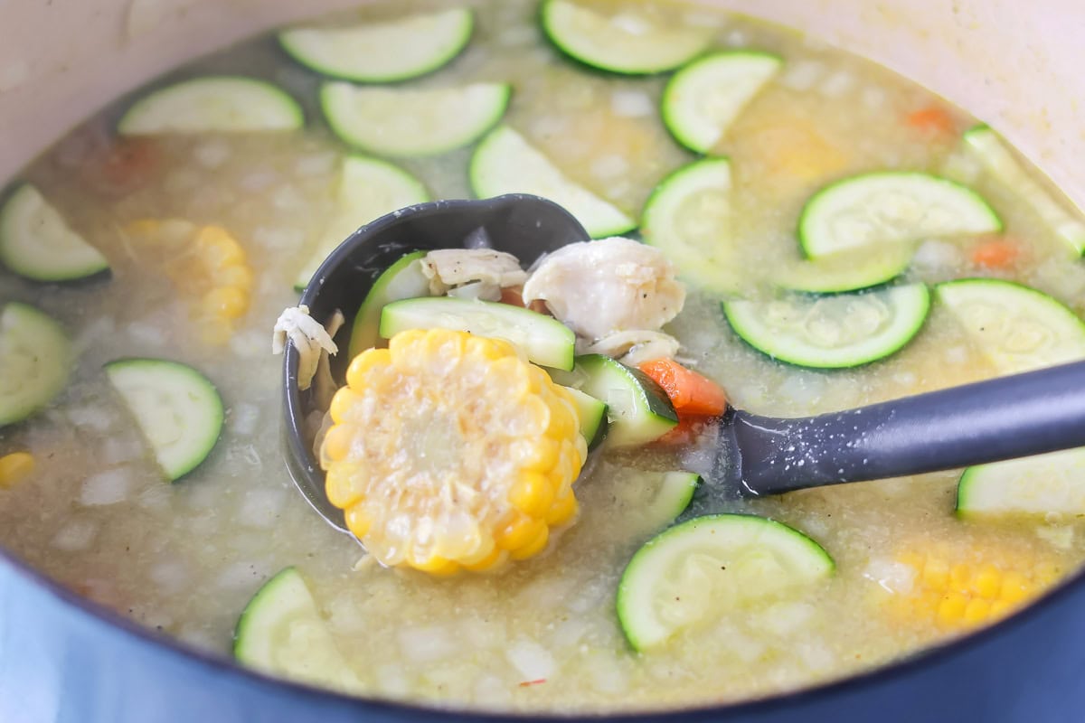 Grandma's famous caldo de pollo is a cozy chicken soup filled with chicken, rice, and Mexican spices and flavors! Simmering caldo de pollo soup.