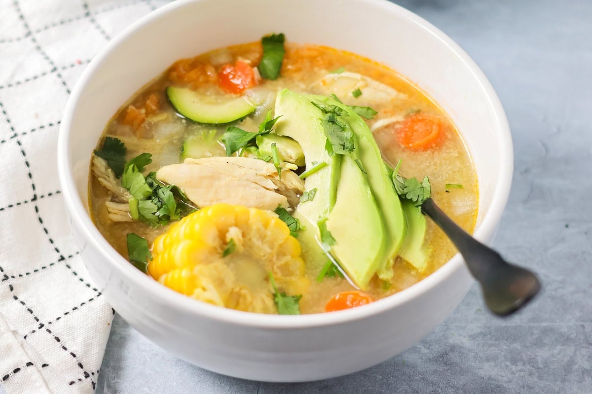 Grandma's famous caldo de pollo is a cozy chicken soup filled with chicken, rice, and Mexican spices and flavors! A serving bowl of caldo de pollo soup.