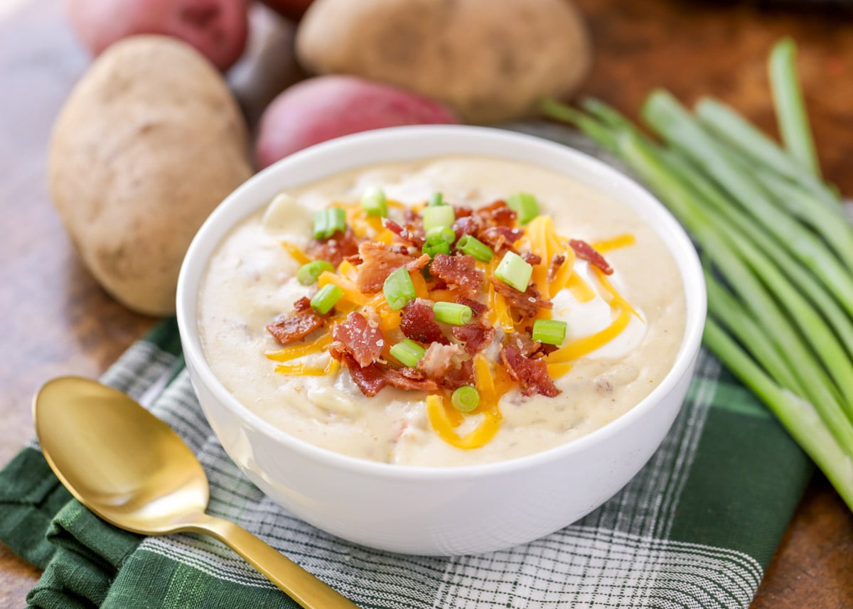 Disney Recipes - Baked Potato Soup topped with bacon and green onions in a white bowl.