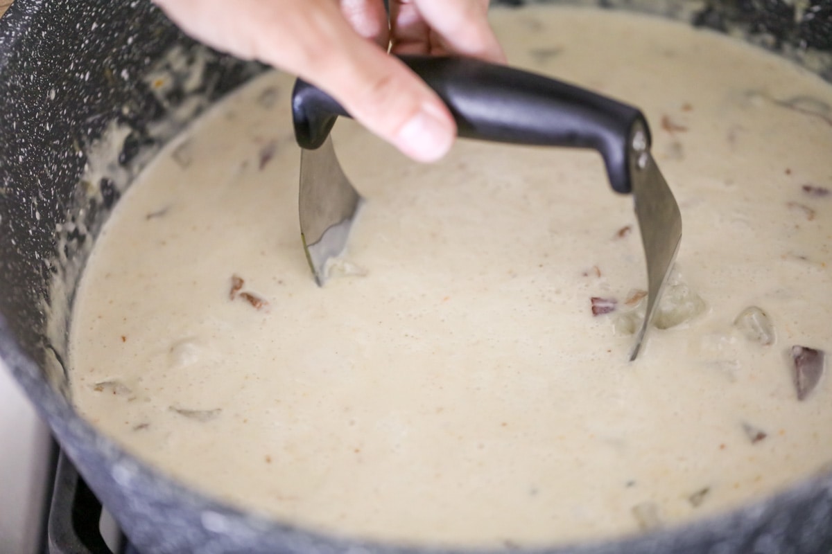 Mashing potatoes in the creamy baked potato soup.