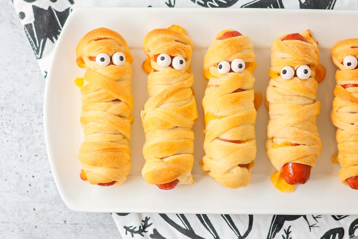 Mummy hot dogs on white serving platter.