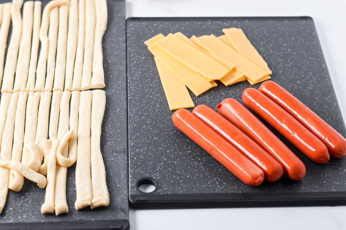 Process picture showing how to wrap mummy dogs on cutting board.