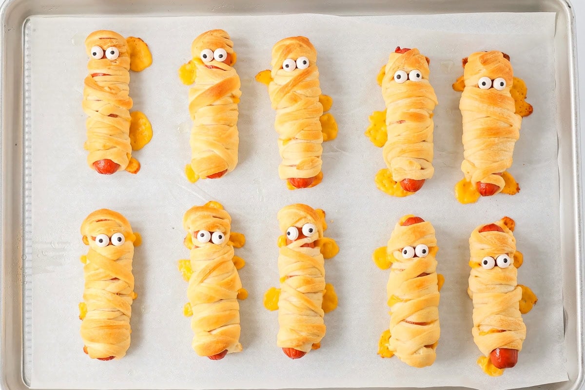 Mummy hot dogs baked on parchment paper lined baking sheet.