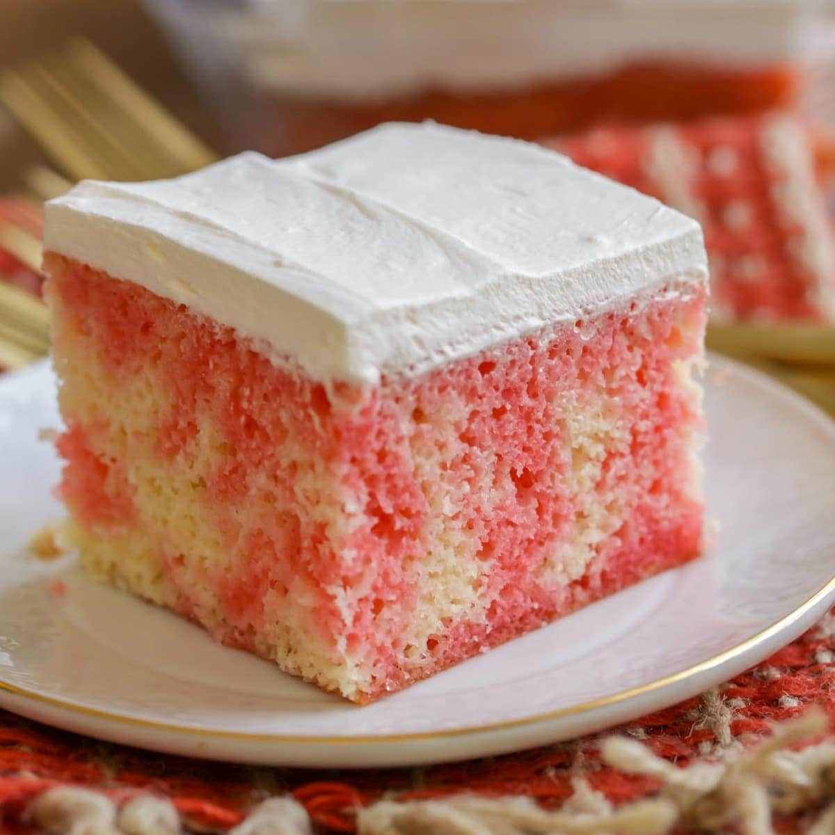 Easy Cake Recipes - A slice of Jello Poke Cake on a white plate.