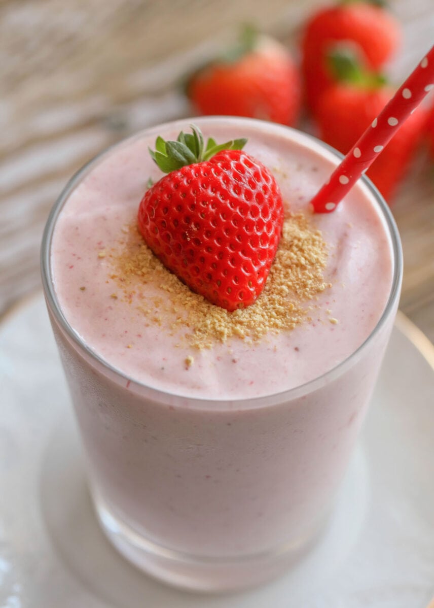 Strawberry flavored cheesecake smoothie in a glass with a straw