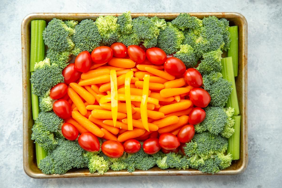 Super Bowl Appetizers - Raw vegetables in the shape of a football on a metal baking sheet. 