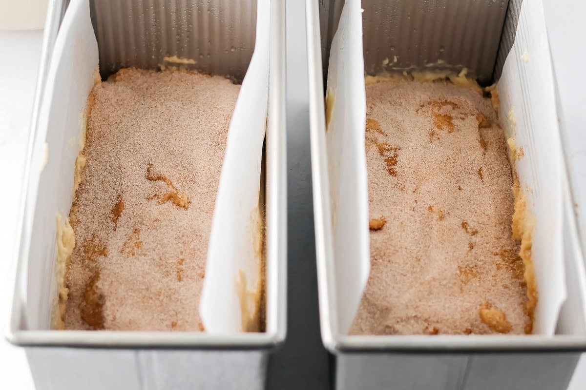 Cinnamon sugar poured over bread batter in pans.