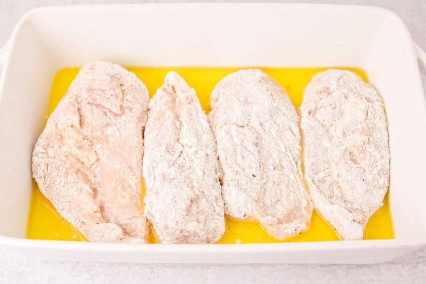 Chicken dredged in flour and in baking dish with butter