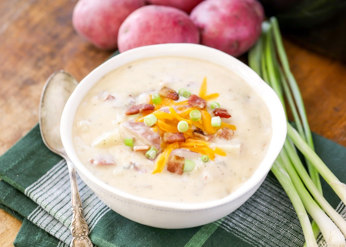 Easy soup recipes - Cheese and chive topped crock pot baked potato soup in a white bowl.