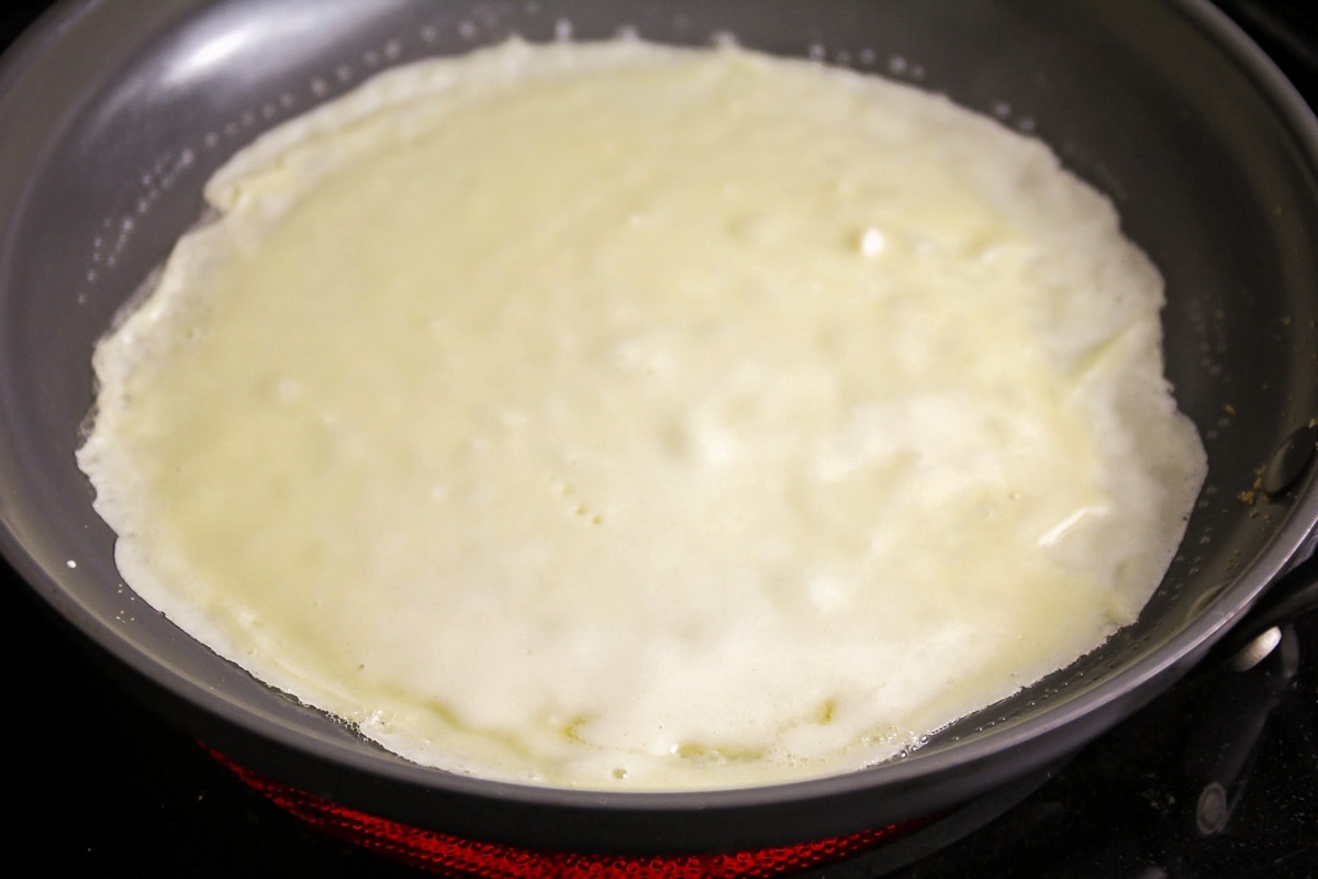 Crepe cooking in a fry pan.