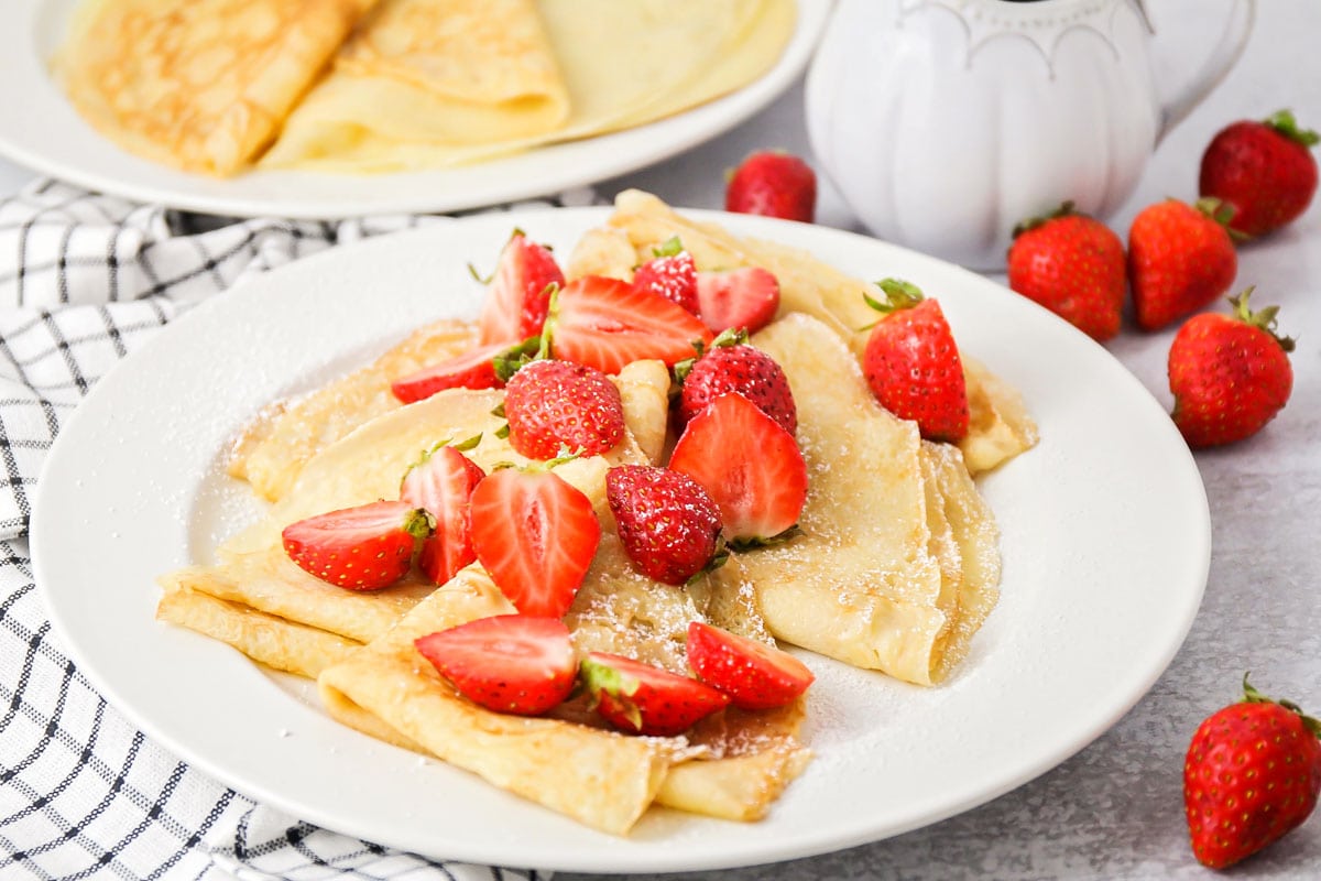 Christmas breakfast ideas - a plate of crepes topped with fresh sliced strawberries.