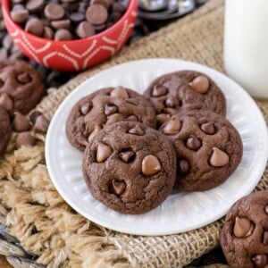 Four double chocolate chip cookies on a white plate.