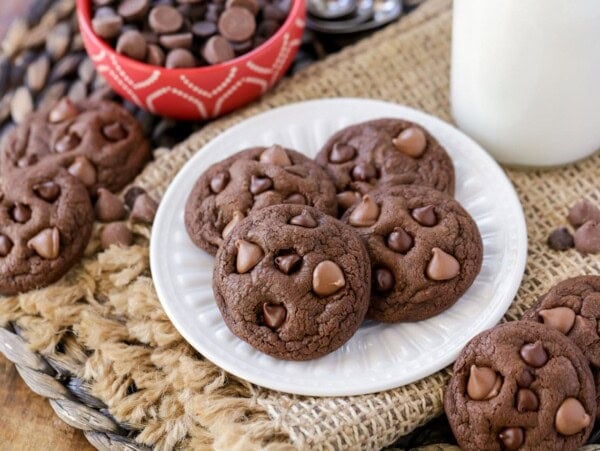 Four double chocolate chip cookies on a white plate.