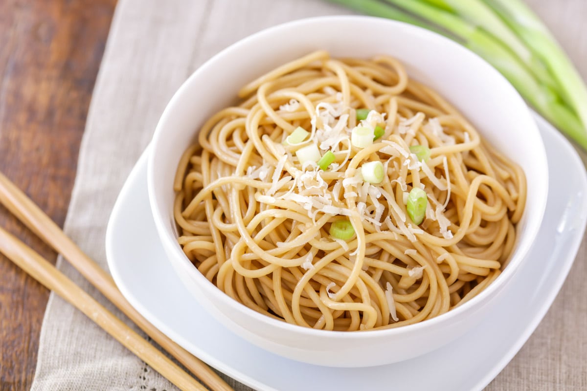 Garlic noodles served in a white bowl. with chopsticks.