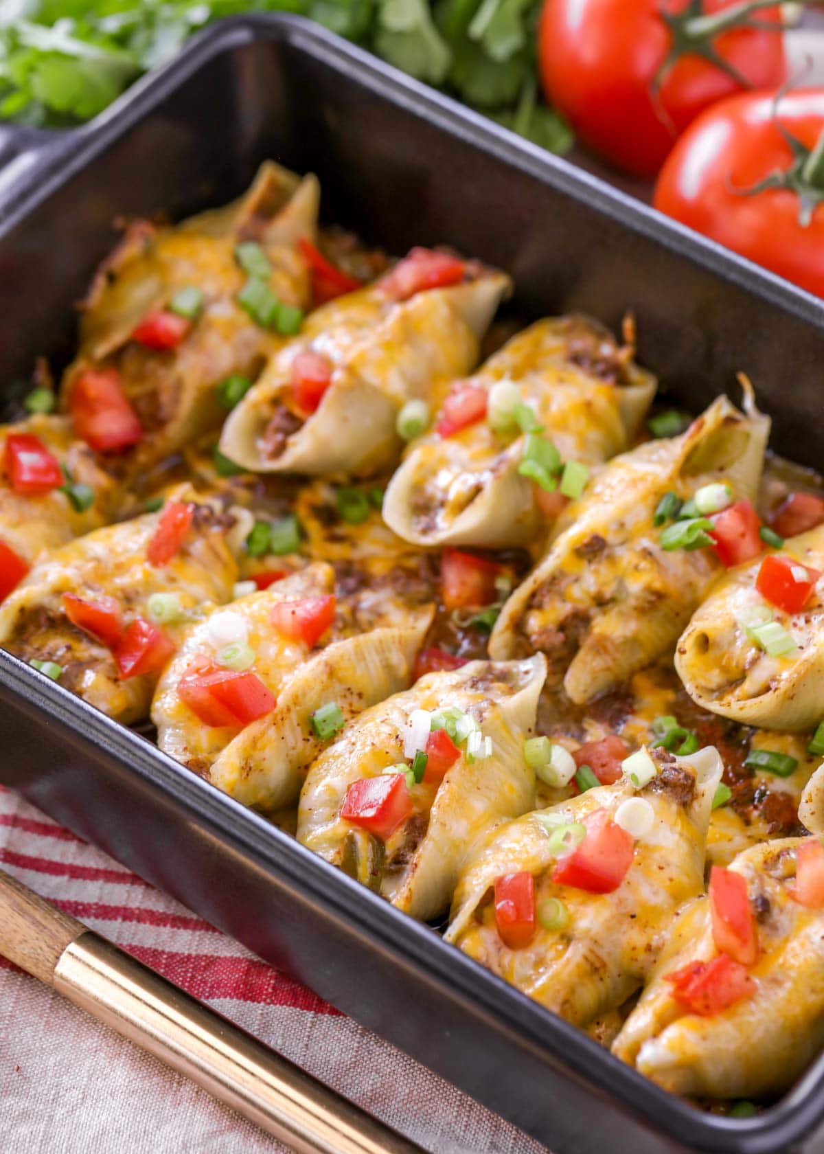 Taco stuffed pasta shells topped with tomatoes and green onion.