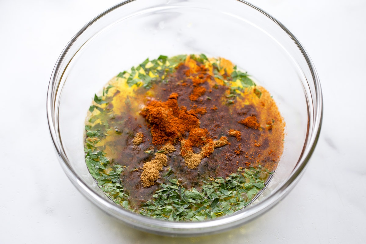 We love carne asada! If you want the meat to be juicy and flavorful, then this simple Carne Asada Marinade is the perfect one to use for it! Mixing ingredients for carne asada marinade recipe in a glass bowl