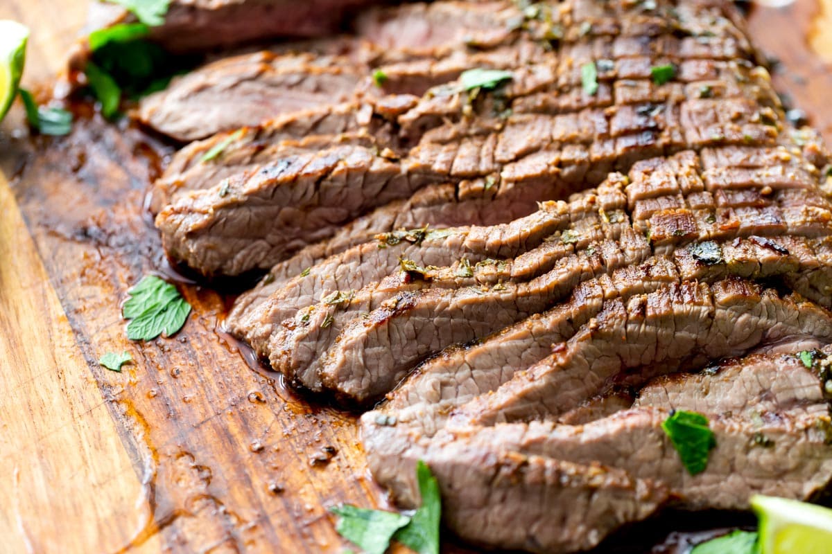 Sliced grilled steak on a wooden board.