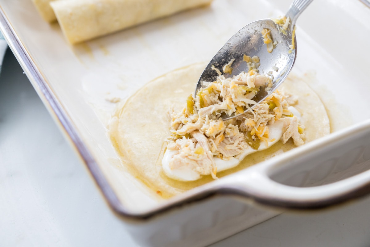 How to make chicken enchiladas by adding chicken filling and sour cream to a corn tortilla