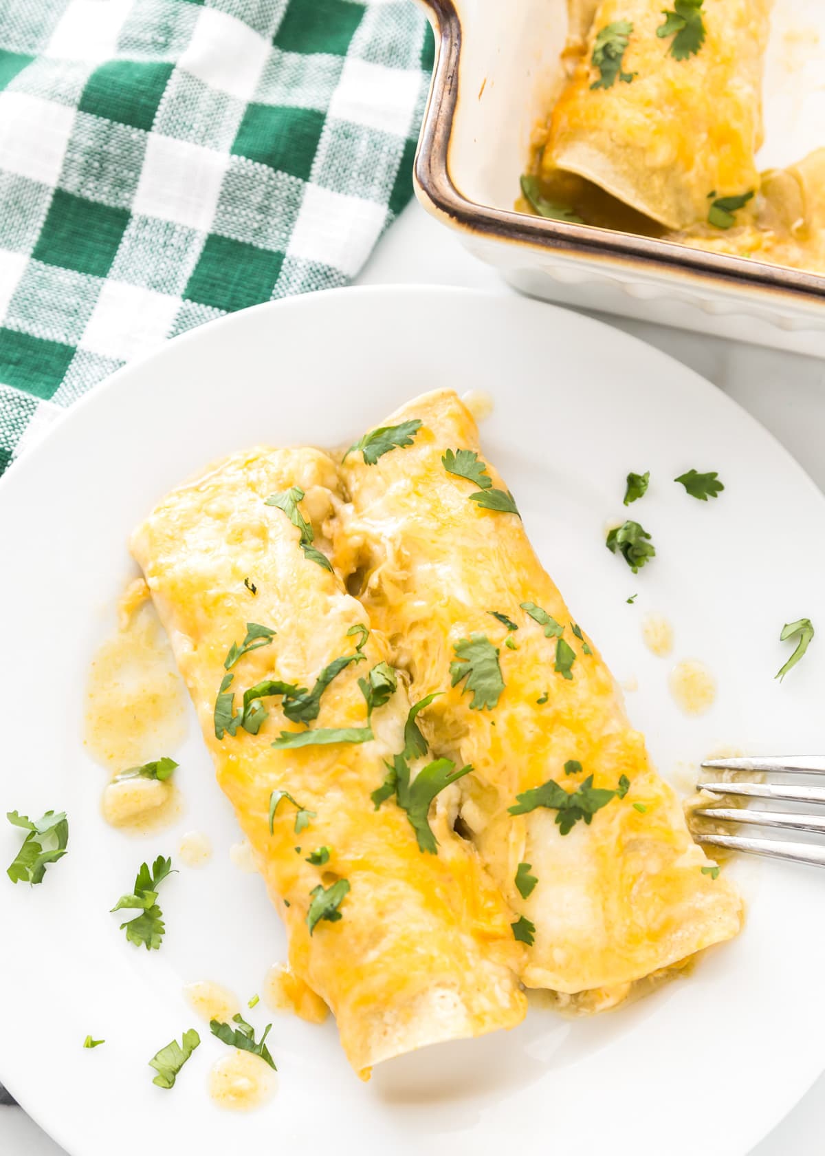 Two homemade Green chile chicken chicken enchiladas served on a white plate
