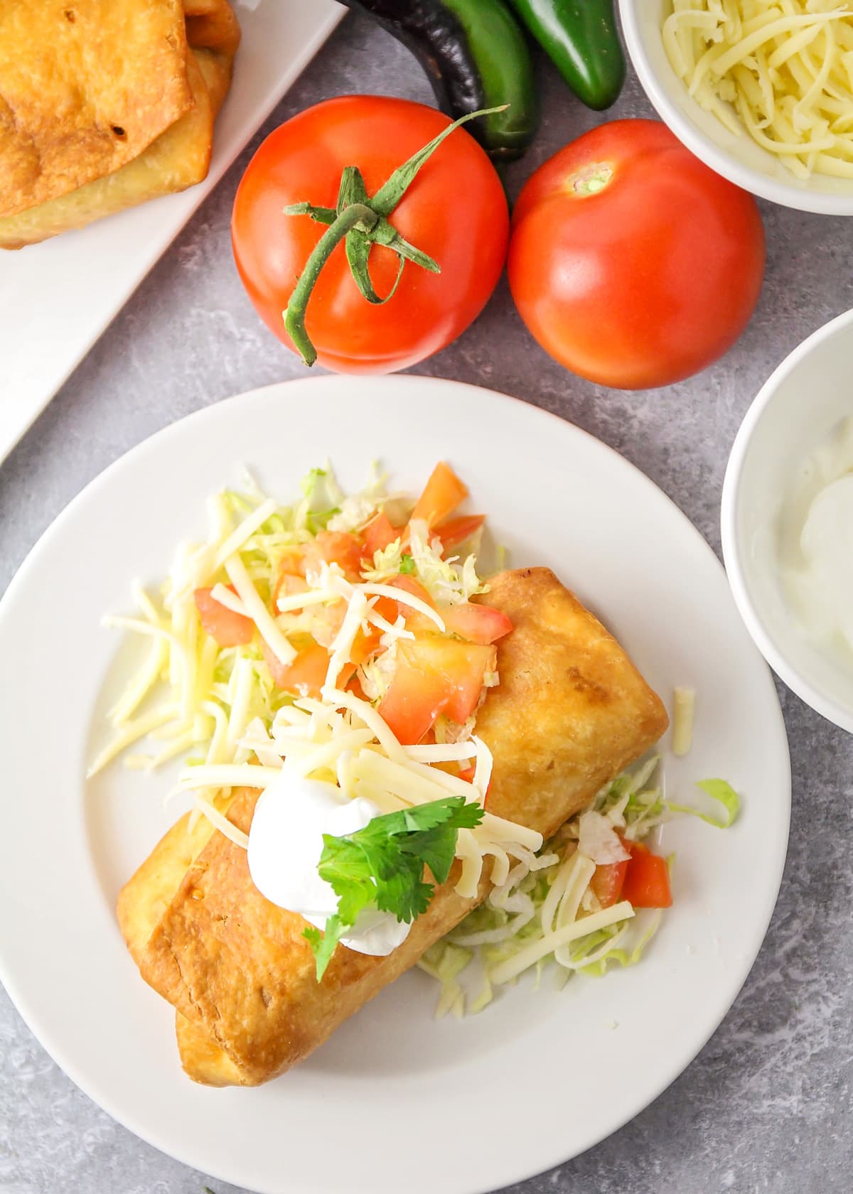 Chimichanga recipe garnished with cheese and served on a white plate.
